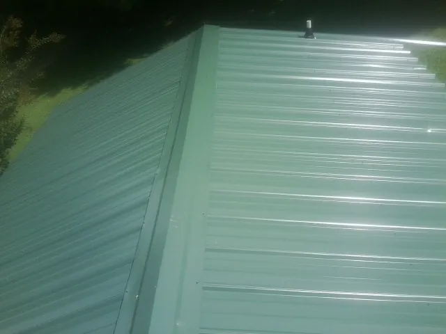 New green metal panels meeting at the ridge of a roof — Flat Roof Repair work by our crew in Beaufort