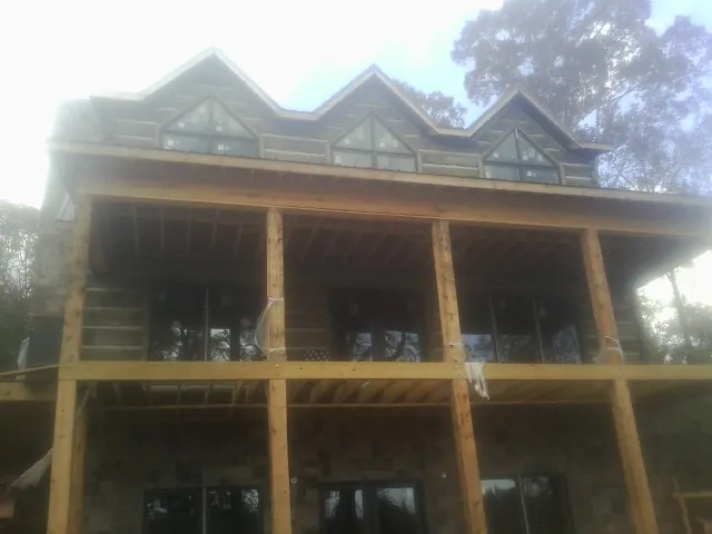 Dormers and porch framing on a large log home under construction — Roof Coating work by our crew in Beaufort