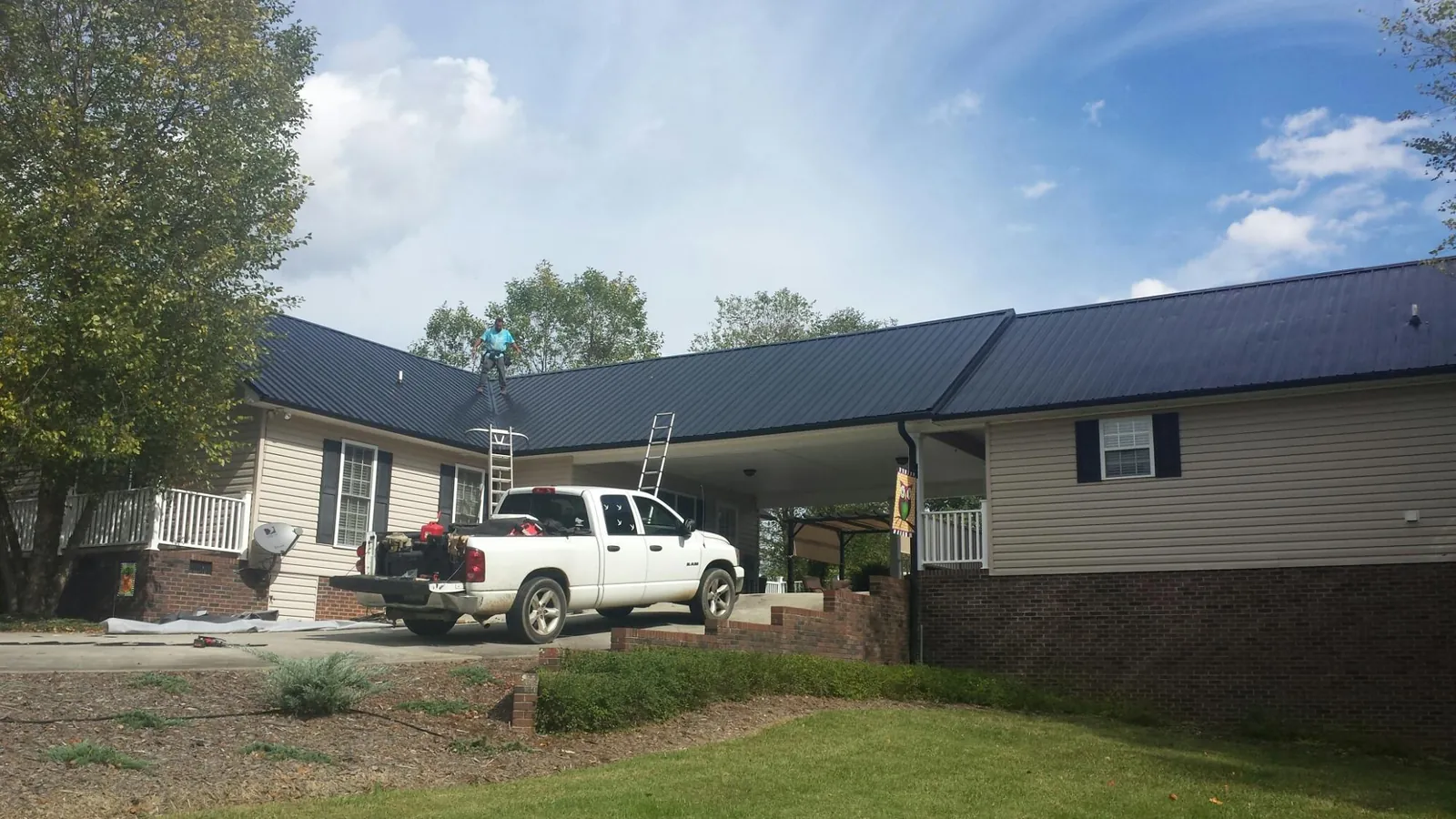 Black metal roof over a home and attached breezeway with ladders set in Beaufort