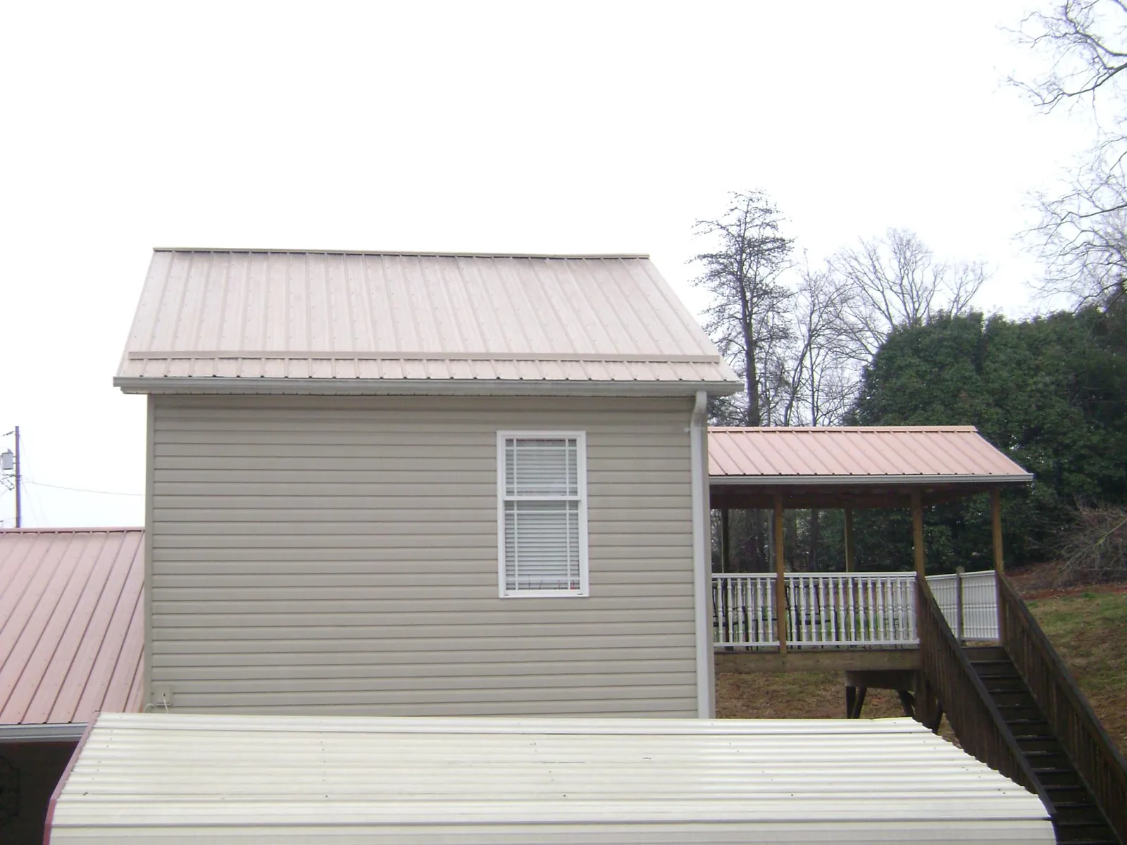Tan metal roofs on a two story addition and attached porch, from a Roof Replacement job in Beaufort