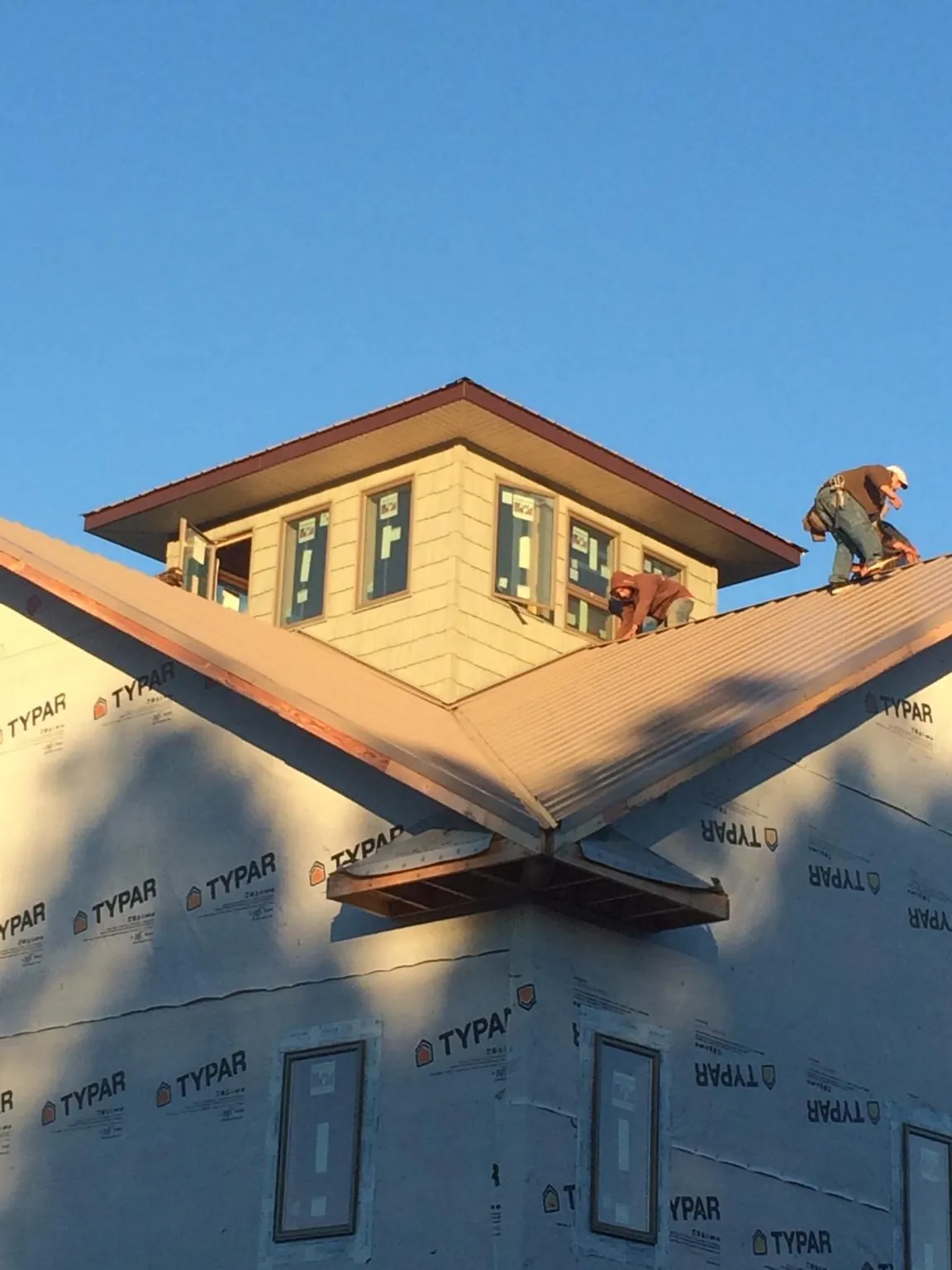 Roofers working around a rooftop cupola on a new metal roof at sunset — Roof Waterproofing in Beaufort by Roofing Brothers